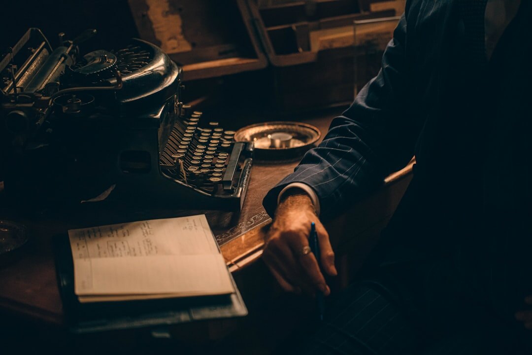 Close up of hands typing on an old typewriter with papers scattered nearby